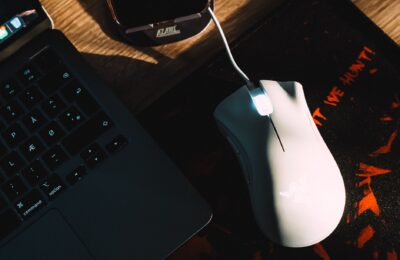 Stylish workspace setup featuring a gaming mouse and laptop with dramatic lighting.