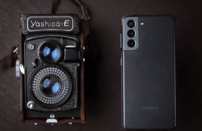 A vintage Yashica camera next to a modern smartphone, showcasing old and new technology.