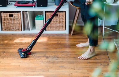 A person vacuuming wooden flooring in a cozy room, emphasizing clean living space.