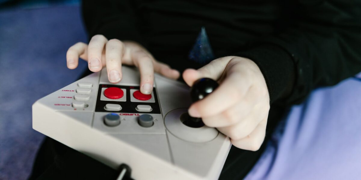 Hands gripping a retro gaming console joystick, showcasing classic gaming technology.