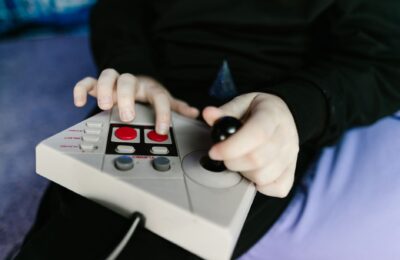 Hands gripping a retro gaming console joystick, showcasing classic gaming technology.