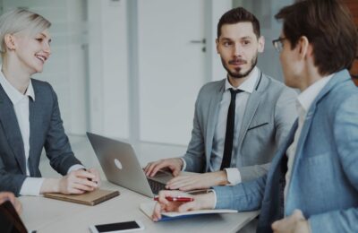 Business professionals in a meeting with laptops and notebooks, discussing strategy.