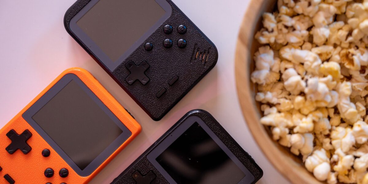 Close-up of retro handheld game consoles and popcorn, perfect for gaming nights.