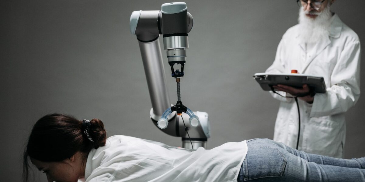 A woman receives a robotic massage as a scientist monitors, showcasing modern technology.