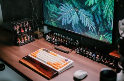 Modern desk setup featuring a custom keyboard, monitor, and collectible figurines for a tech-savvy workspace.