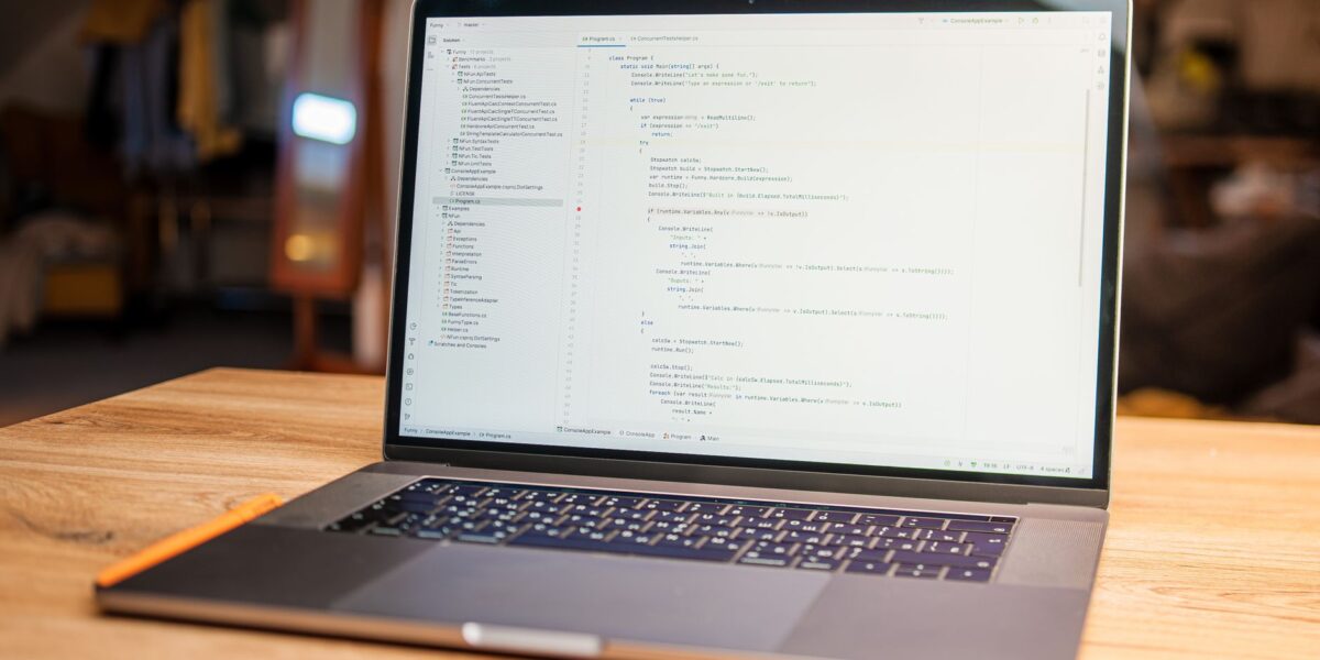 Open laptop with visible code on screen on a wooden desk in a modern, cozy workspace.