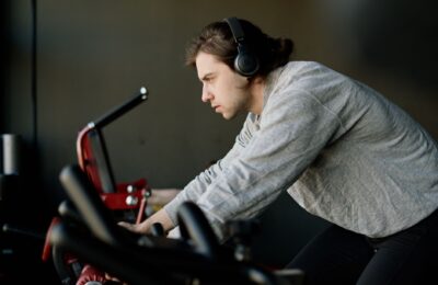 Determined young man training on exercise bike in gym, wearing headphones.