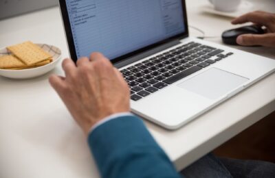 A person working on a laptop at a desk with snacks, emphasizing productivity and technology.