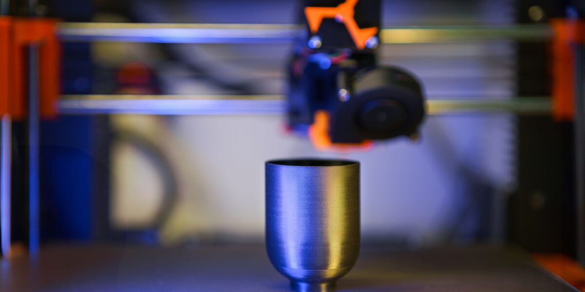 Innovative close-up of 3D printer crafting a metallic object, showcasing modern technology.