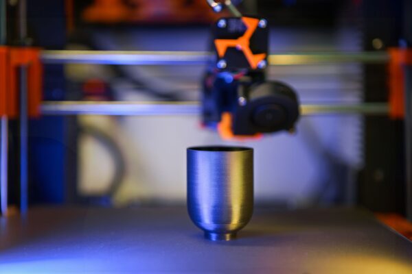 Innovative close-up of 3D printer crafting a metallic object, showcasing modern technology.