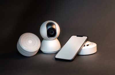 A sleek smartphone with modern smart home devices on a minimalist gray background.