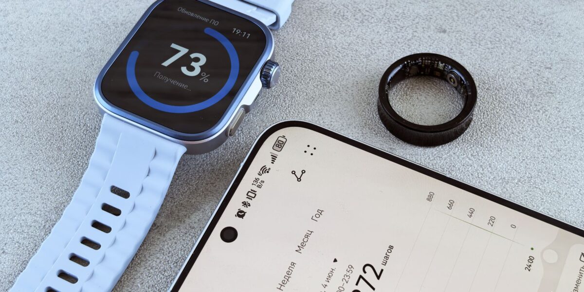 Smartwatch with fitness data, smartphone, and health ring on a gray surface.