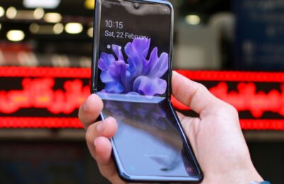 Close-up of a modern flip smartphone held in hand, showcasing innovative technology outdoors in a bustling city.