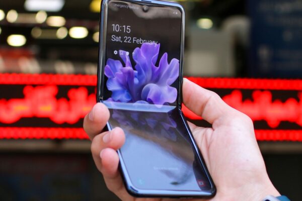 Close-up of a modern flip smartphone held in hand, showcasing innovative technology outdoors in a bustling city.