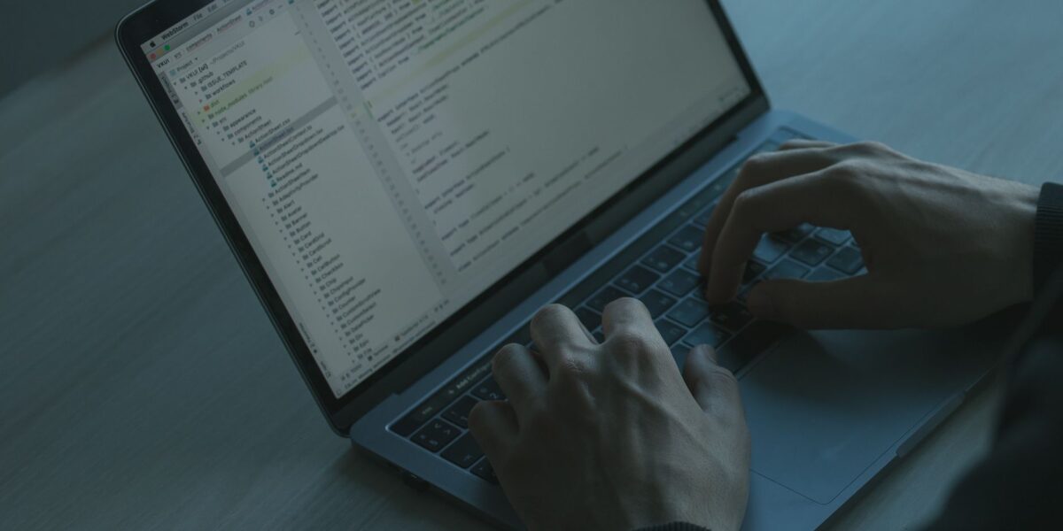 A person typing code on a laptop with a focus on cybersecurity and software development.