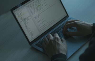 A person typing code on a laptop with a focus on cybersecurity and software development.