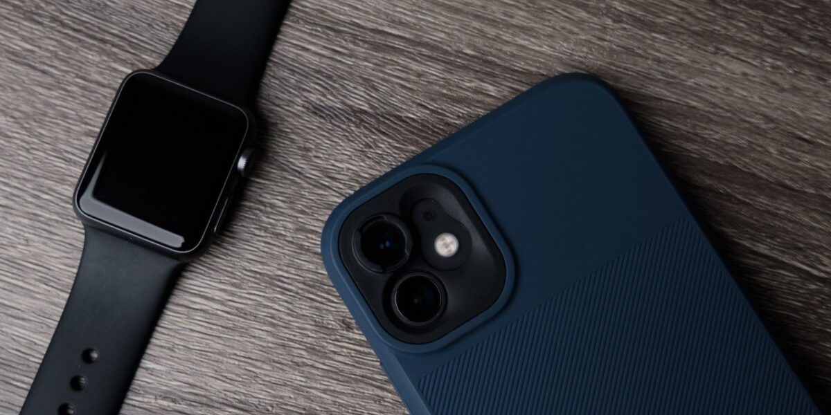 Close-up of a smartwatch and smartphone on a wooden surface, showcasing modern technology.
