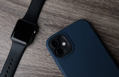 Close-up of a smartwatch and smartphone on a wooden surface, showcasing modern technology.