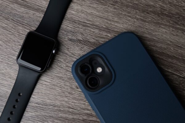 Close-up of a smartwatch and smartphone on a wooden surface, showcasing modern technology.