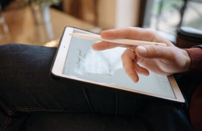 Close-up of a hand holding a stylus, writing on a tablet, featuring handwritten notes. Ideal for digital creativity concepts.