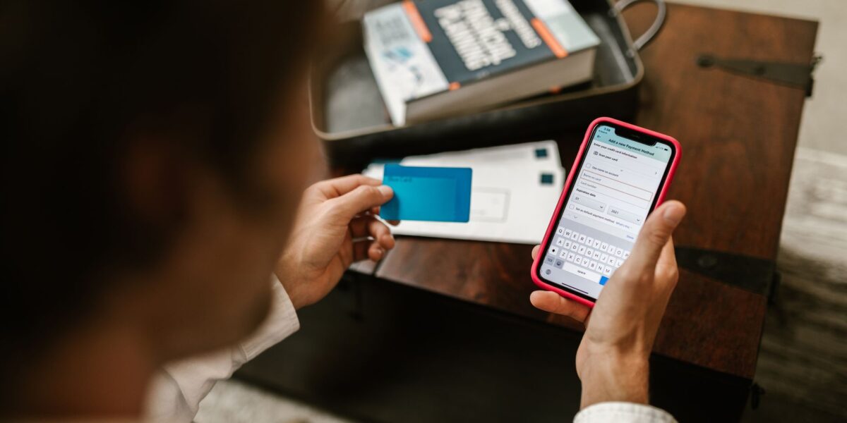 Person making an online payment using a smartphone and credit card indoors.