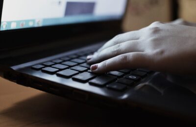 A close-up view of a person typing on a laptop keyboard indoors.
