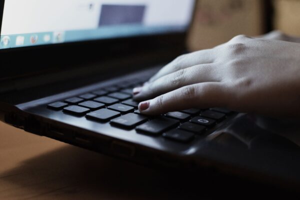 A close-up view of a person typing on a laptop keyboard indoors.