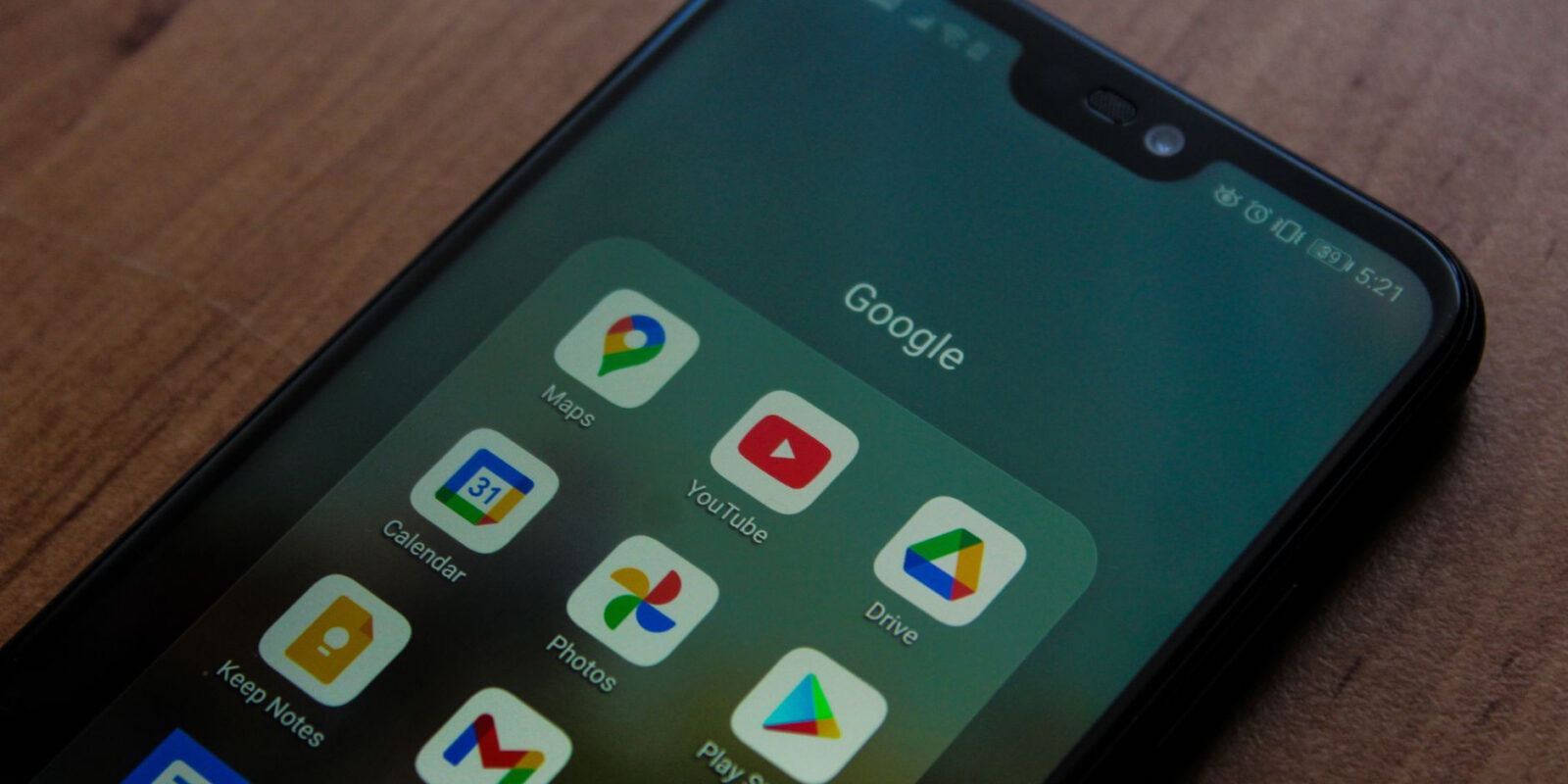 Close-up of a smartphone showing various Google apps on its screen.