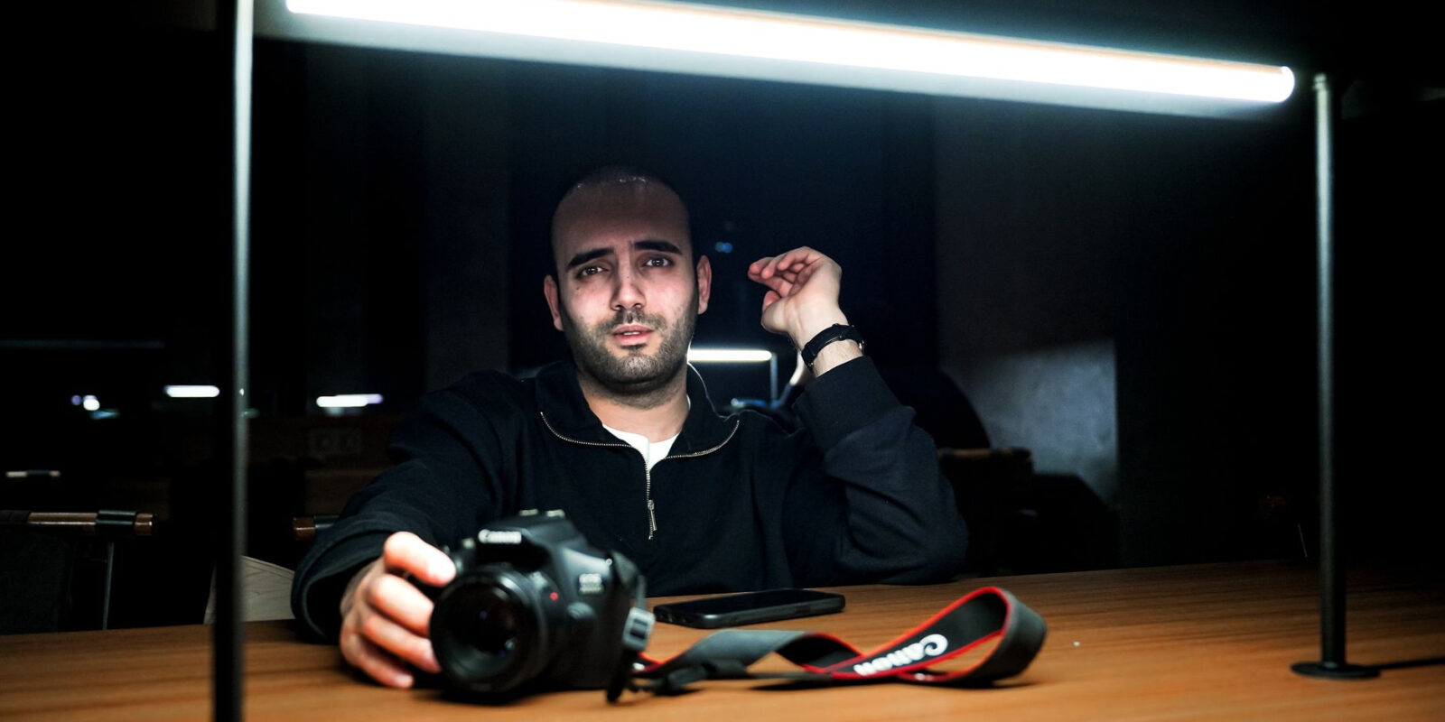 A striking portrait of a photographer with a camera under dramatic lighting.