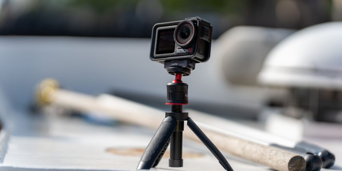 Close-up of a compact action camera mounted on a mini tripod outdoors.