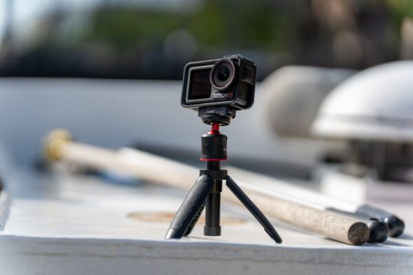 Close-up of a compact action camera mounted on a mini tripod outdoors.