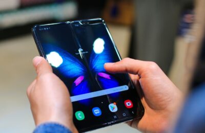 Close-up of hands holding a foldable smartphone showing a butterfly on the screen.