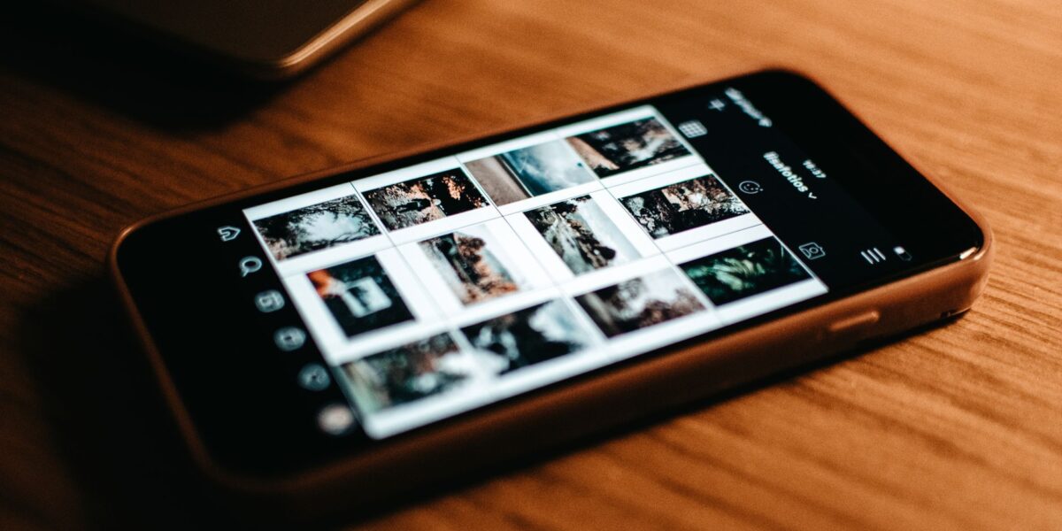 Close-up of smartphone showing photo gallery on wooden desk.