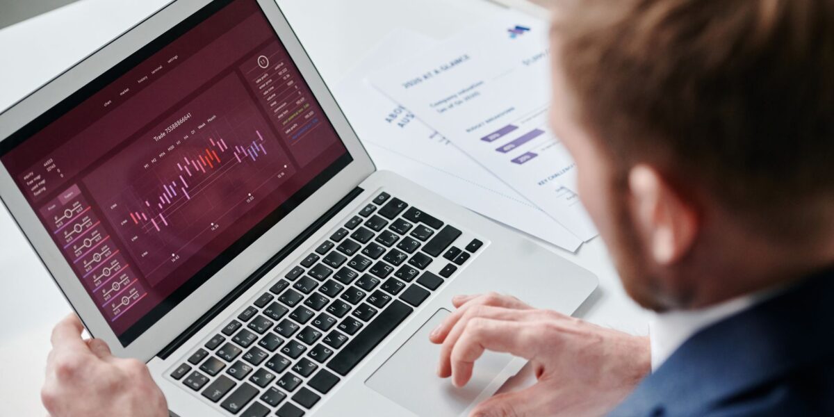 Businessman reviewing data analytics dashboard on laptop in bright office.