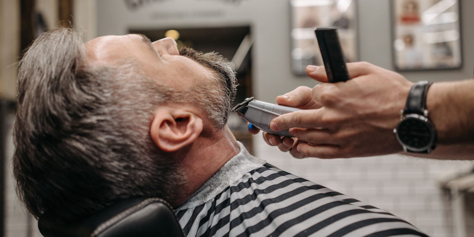 Close-up of a man getting a beard trim in a stylish barbershop. Professional grooming in modern setting.