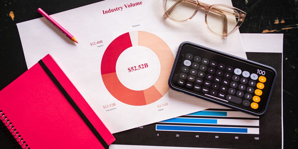 Stock photo of business charts, calculator, and eyeglasses on a desk.