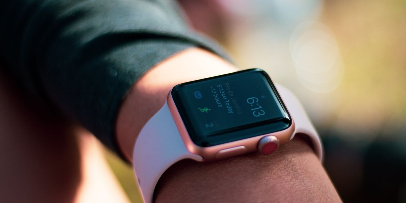 Smartwatch with digital screen displaying 6:13, worn on wrist outdoors.