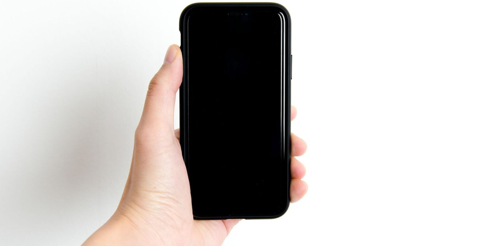 Simple image of a hand holding a black smartphone with a white background, emphasizing minimalism and technology.