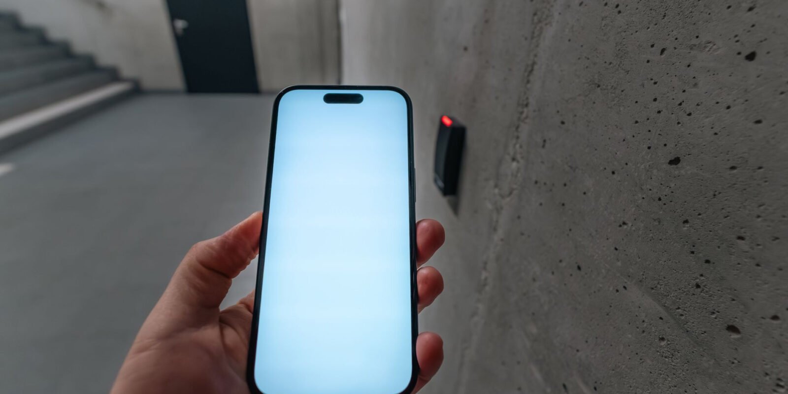 A smartphone unlocking a secure door using NFC technology in a modern building stairwell.