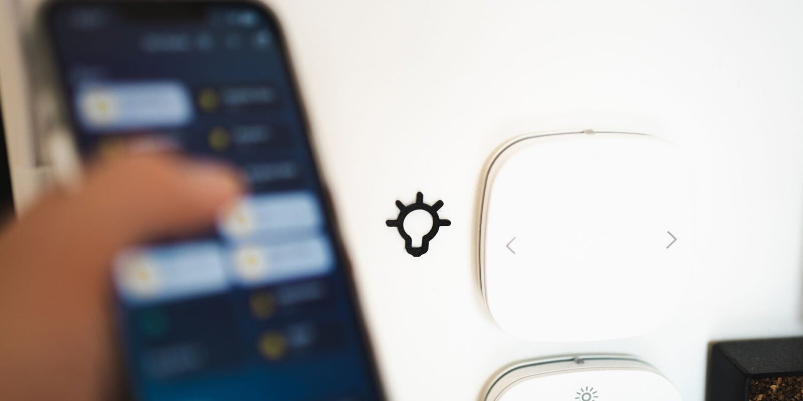 Blurry smartphone controlling smart home tech on a wall.
