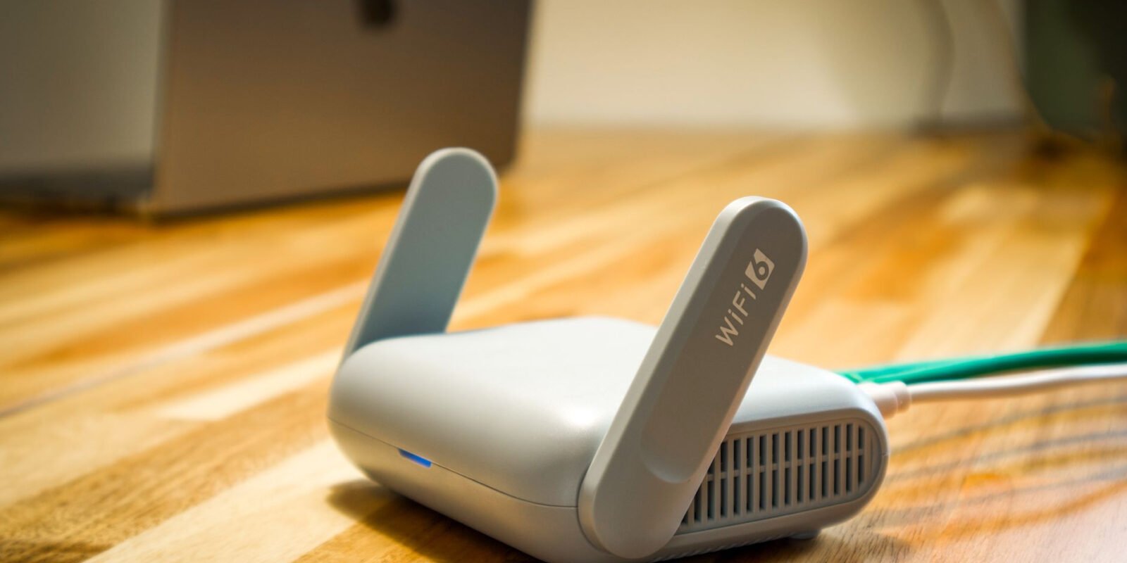 A sleek WiFi 6 router with antennas and cable on a wooden desk, perfect for modern home networks.